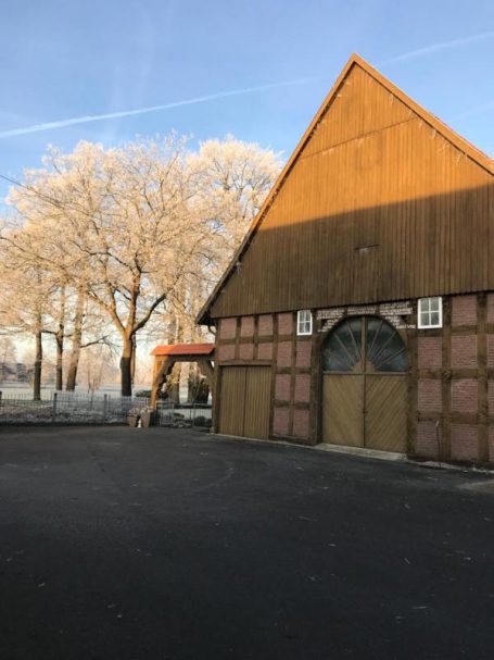 Historisches Fachwerkgebäude mit Bäumen und klarem blauen Himmel im Hintergrund.
