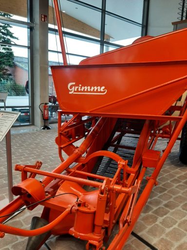 Roter landwirtschaftlicher Schlepper mit Vorrichtung zur Bodenbearbeitung.