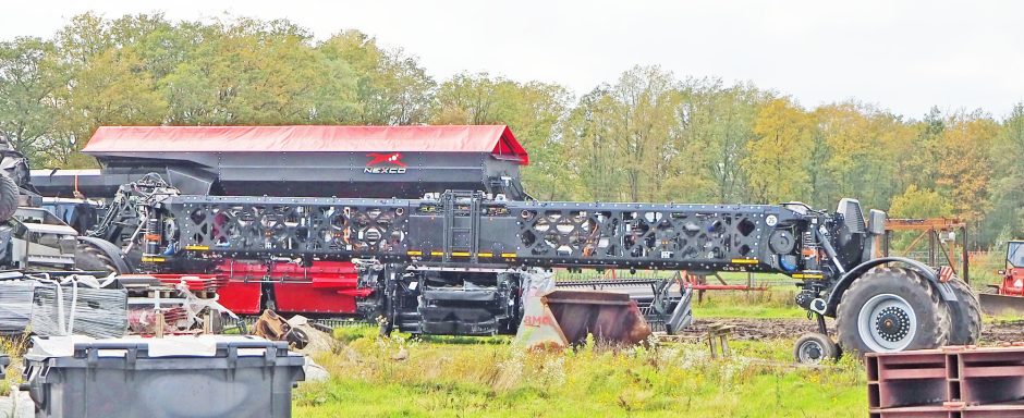 Schwarzer Landmaschinen mit rotem Aufsatz auf einem weitläufigen Feld.