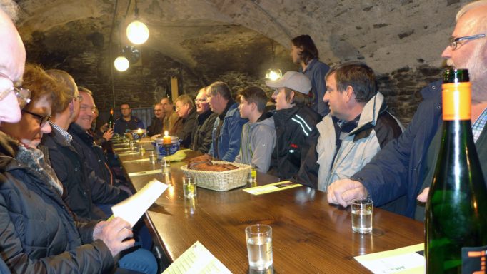 Eine lange Tafel an der Menschen sitzen für eine Weinverkostung.