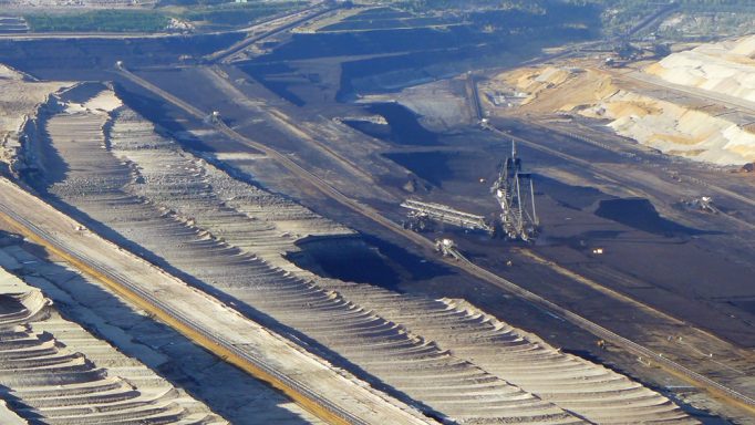 Braunkohletagebau mit großen Abraumhalden und Förderanlagen in einer offenen Landschaft.