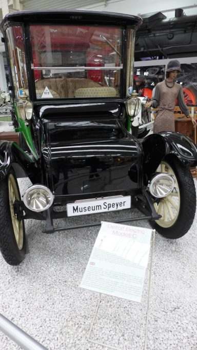 Historisches schwarzes Auto mit runden Scheinwerfern und einem Schild vorne.