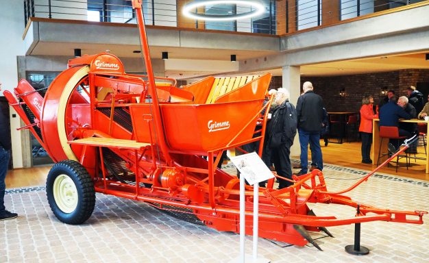 Roter landwirtschaftlicher Mähdrescher im Ausstellungsraum mit Besuchern.