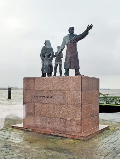 Bronzestatue eines Mannes mit zwei Kindern und einer Frau, stehend auf einem Sockel.